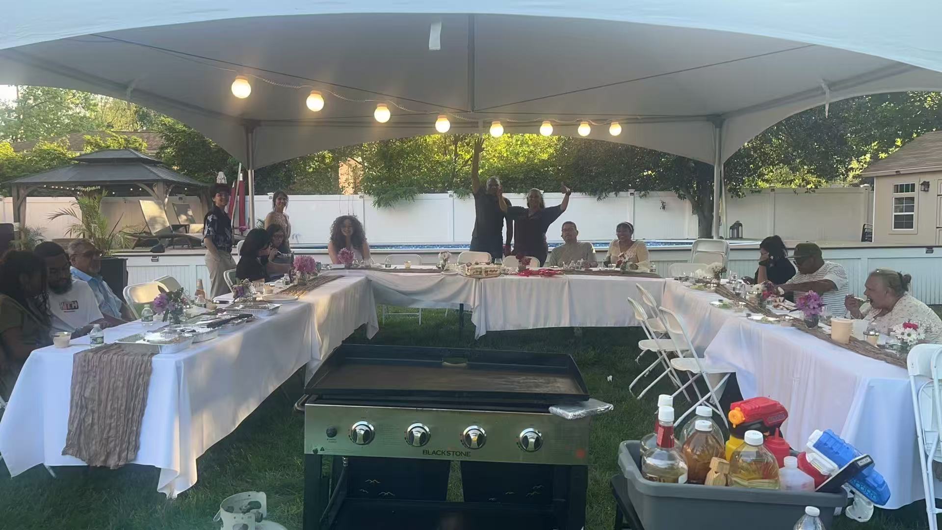 Elegant outdoor tent party with string lights and Blackstone hibachi grill setup