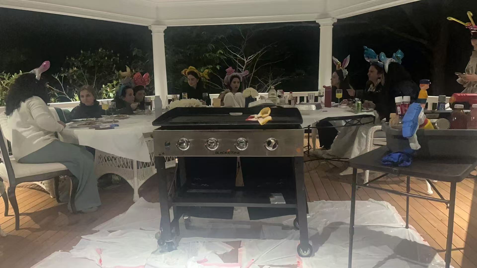 Evening gazebo party with hibachi grill and guests wearing party headbands